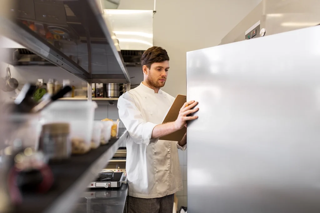 Chef using a commercial refrigerator in a professional kitchen